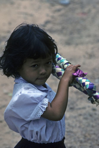 Portrait of small girl holding colorful plaited tubes at Angkor