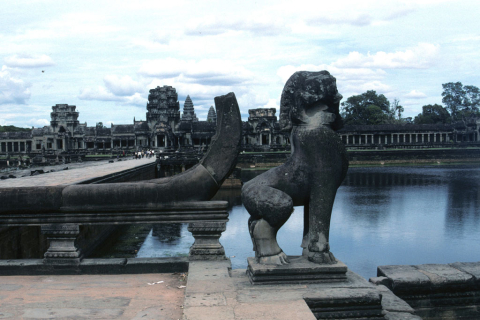 Moat, guardian lion statue, and causeway into temple buildings at Angkor Wat