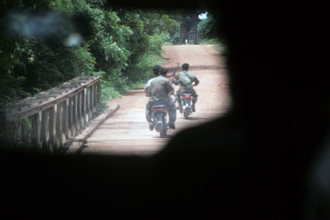 Three men on two motorcycles provide tourist escort to Banteay Srei Temple