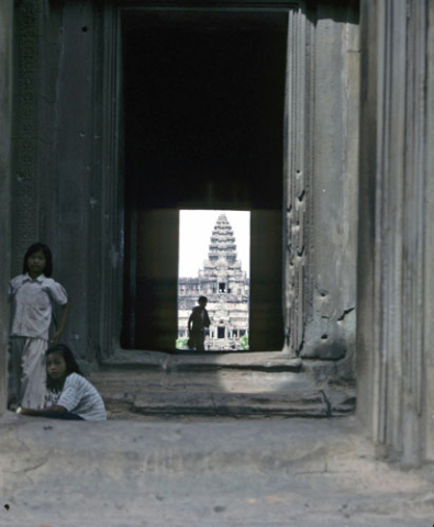 Two girls by illuminated doorway view of central tower at Angkor Wat