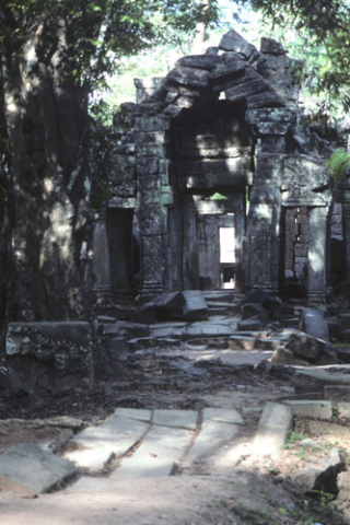 Crumbling stone arch over doorway at Ta Prohm site at Angkor