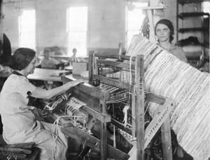 Women making rugs on a loom.